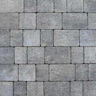 Close-up image of Brett Alpha 50mm block paving in Charcoal, displaying deep grey tones and a tumbled, aged finish. The paving blocks are tightly laid in a uniform pattern, ideal for driveways or pathways seeking a sleek, modern appearance with durable performance