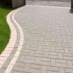 Curved residential driveway featuring Brett Omega 50mm Block Paving in Silver Haze, laid in a herringbone pattern with contrasting light grey edging for a clean, modern finish