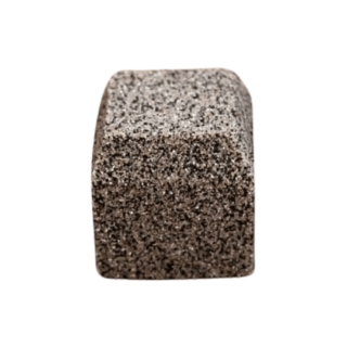 Front-facing view of a charcoal grey block paving brick with a coarse, speckled texture and slightly curved sides, displayed on a clean white background